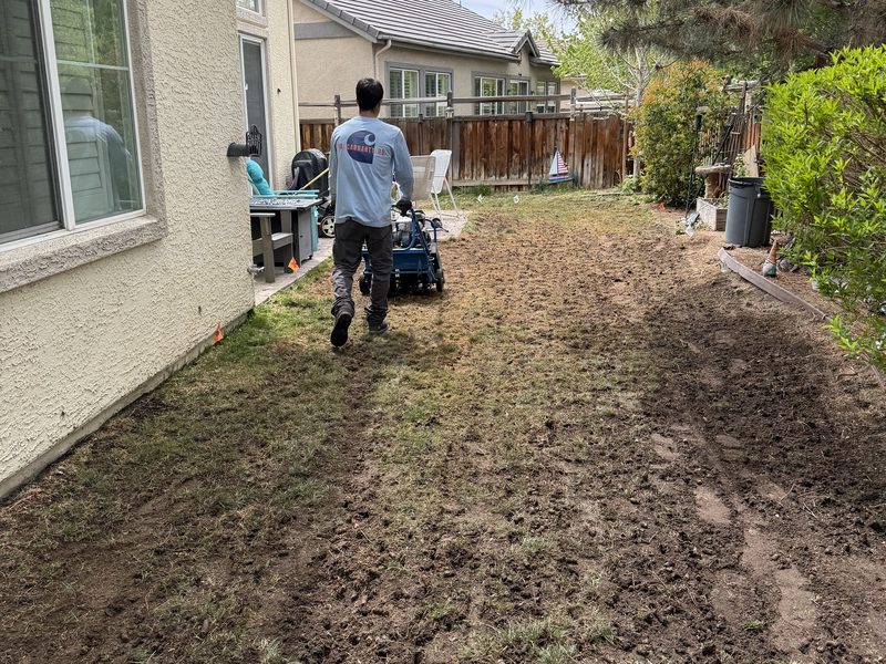Crew member core-aerating a backyard lawn for Spanish Springs Lawn Care